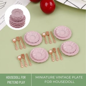 Puede incluir: Un juego de platos rosa en miniatura y cubiertos dorados para jugar a la casa de muñecas. Los platos tienen un borde festoneado y un diseño floral. Los cubiertos incluyen tenedores, cuchillos y cucharas.