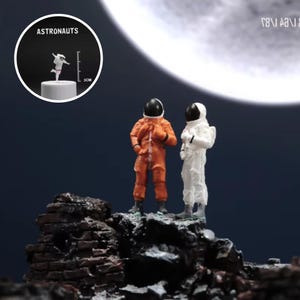 Puede incluir: Dos astronautas, uno con un traje espacial naranja y otro con un traje espacial blanco, se paran en una superficie rocosa con una gran luna brillante en el fondo.