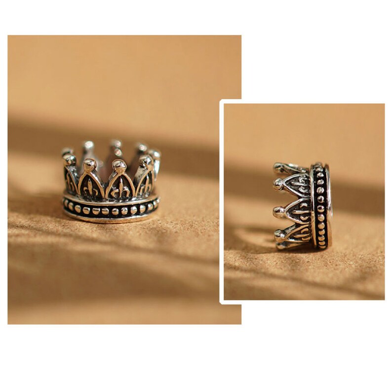 May include: A silver crown ring with a beaded band. The crown has a detailed design with pointed arches.
