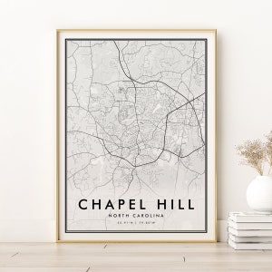 May include: A black and white map print of Chapel Hill, North Carolina. The map shows the streets and roads of the city. The text "Chapel Hill, North Carolina, 35.91°N | 79.05°W" is printed below the map.