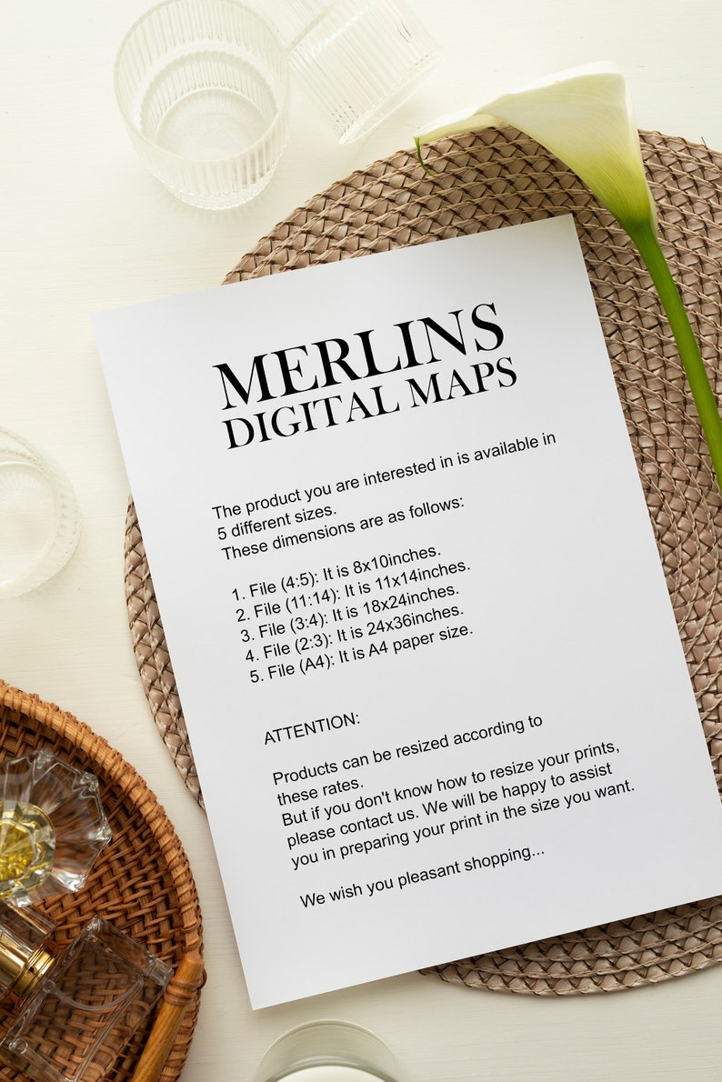Peut inclure: Une feuille de papier blanche avec le texte "MERLINS DIGITAL MAPS" et des options de taille. Le papier est pos&eacute; sur un dessous de plat tiss&eacute;, avec une fleur blanche et des objets en verre en arri&egrave;re-plan. Les tailles sont 20x25, 28x36, 46x61, 61x91 cm, et A4.