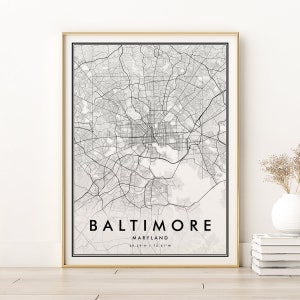May include: Black and white city map print of Baltimore, Maryland with the city name and coordinates at the bottom. The map is framed in a gold frame.