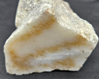 May include: A large, white, and brown agate rock with a rough, natural texture. The rock has a unique, swirling pattern of brown and white.