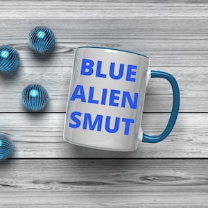 May include: White ceramic mug with a blue rim and handle. The mug has the words "BLUE ALIEN SMUT" printed in blue on the front.
