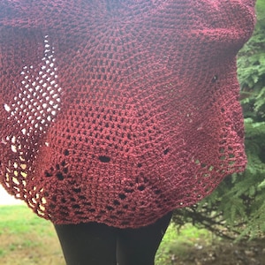 May include: A maroon crocheted cardigan with a lacy pattern. The cardigan is open in the front and has long sleeves.