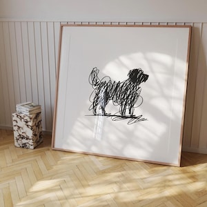 May include: A black and white line drawing of a dog in a simple, modern style. The dog is depicted in a standing position, with its head turned to the side. The drawing is framed in a light wood frame.