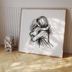 May include: Black and white line drawing of two people hugging. The drawing is framed and hanging on a white wall.