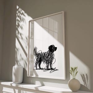 Puede incluir: Una impresión artística enmarcada con una ilustración abstracta en negro de un perro sobre un fondo blanco. La obra de arte está en un marco blanco y se exhibe en una estante blanco. La imagen está iluminada por luz natural, proyectando sombras.