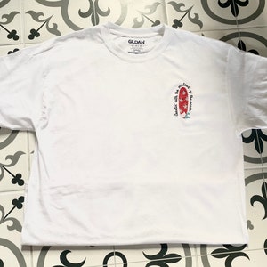 May include: White t-shirt with a red and white surfboard graphic and the text "Cruisin' with the motion of the ocean".