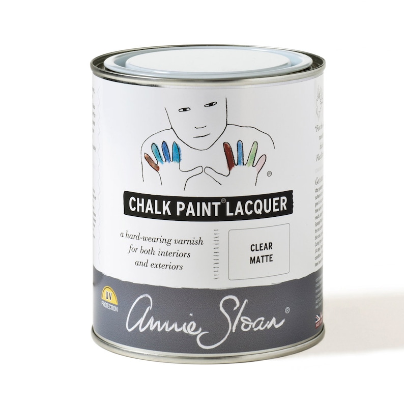 May include: A white can of Annie Sloan Chalk Paint Lacquer in a clear matte finish. The can has a black label with the text "Chalk Paint Lacquer" and "a hard-wearing varnish for both interiors and exteriors". The can also has a UV protection logo.