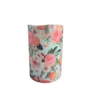Candela a colonna in cera senza fiamma a LED con fiori romantici e arance su sfondo verde acqua