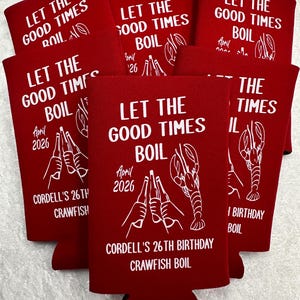 May include: Red can coolers with white text that reads "LET THE GOOD TIMES BOIL" and "CORDELL'S 26TH BIRTHDAY CRAWFISH BOIL". The design includes illustrations of hands toasting beer bottles and a crawfish.