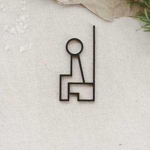May include: Black silhouette of a person sitting on a chair. The chair has a tall back and a simple design.