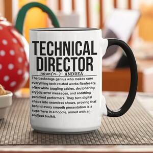 May include: White ceramic mug with a black rim and handle. The mug features black text that reads "TECHNICAL DIRECTOR noun(n.) ANDREA The backstage genius who makes sure everything tech-related works flawlessly, often while juggling cables, deciphering cryptic error messages, and soothing panicked performers. They turn digital chaos into seamless shows, proving that behind every smooth presentation is a superhero in a hoodie, armed with an endless toolkit."