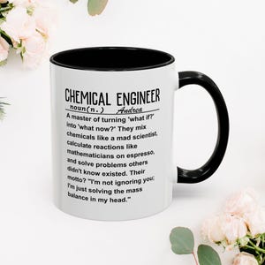 May include: A white ceramic mug with a black interior and handle. The mug features the text "CHEMICAL ENGINEER" with a definition and the name "Andrea". The mug is decorated with a floral arrangement.