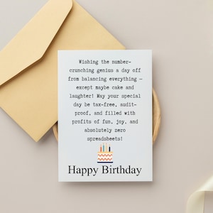 Op de afbeelding: Een verjaardagskaart met een lichtbeige envelop. De witte kaart heeft de tekst "Wishing the number-crunching genius a day off...Happy Birthday" met een taartafbeelding. De kaart ligt op een lichtbeige oppervlak.