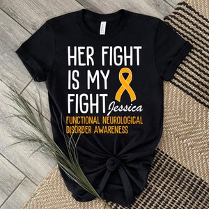 Könnte beinhalten: Schwarzes T-Shirt mit weißem Text, der "Her Fight Is My Fight Jessica Functional Neurological Disorder Awareness" lautet, und einem gelben Band.