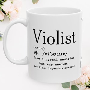 May include: A white ceramic mug featuring black printed text that defines the word Violist as a noun, including a phonetic pronunciation guide and the phrase: Like a normal musician, but way cooler. See Also: legendary, awesome.