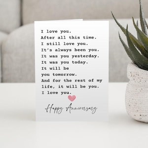 May include: A white greeting card featuring black typewriter-style text that reads: I love you. After all this time. I still love you. It's always been you. It was you yesterday. It was you today. It will be you tomorrow. Happy Anniversary with a pink heart.
