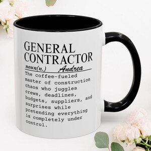 May include: A white ceramic mug with a black interior and handle, featuring black printed text that defines a general contractor as a coffee-fuelled master of construction chaos who manages crews, deadlines, budgets, and suppliers for Andrea.