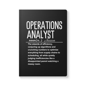 May include: Black and white notebook with the text "OPERATIONS ANALYST noun(n.) Jessica The wizards of efficiency, conjuring up algorithms and crunching numbers to optimize everything from supply chains to scheduling, all while quietly judging inefficiencies like a disappointed parent watching a messy room."