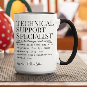 May include: A white ceramic mug with a black handle and rim, featuring black text that reads: TECHNICAL SUPPORT SPECIALIST (tek-ni-kuhl sub-port spesh-uh-list) A user helper who explains solutions clearly, fixes issues quickly, and somehow keeps frustration levels low. See Also: Charlotte.