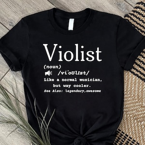 Könnte beinhalten: Ein schwarzes Kurzarm-T-Shirt mit weißem Aufdruck: Violist (noun) /vi'oʊlɪst/ Like a normal musician, but way cooler. See Also: legendary, awesome. Das Oberteil hat einen Rundhalsausschnitt und eine normale Passform mit dem Text auf der Vorderseite.