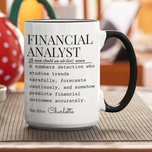 Könnte beinhalten: Eine weiße Keramik-Tasse mit schwarzem Henkel und Rand, bedruckt mit schwarzem Text, der einen Finanzanalysten als einen Zahlendetektiv definiert, der Trends untersucht, vorsichtig prognostiziert und finanzielle Ergebnisse genau vorhersagt.