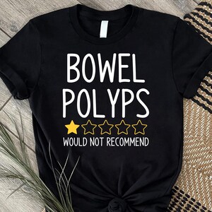 May include: Black t-shirt with white text that reads "BOWEL POLYPS" above a rating of one gold star and four outlined stars. Below the stars, the text reads "WOULD NOT RECOMMEND".