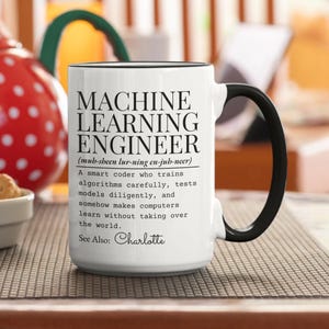 May include: White ceramic mug with a black handle and rim. The mug features the text "MACHINE LEARNING ENGINEER" with a definition and the name "Charlotte" at the bottom. A perfect gift for a computer programmer.