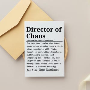 Könnte beinhalten: Eine weiße Karte mit dem Text "Director of Chaos" in fetter schwarzer Schrift, mit einer Definition darunter. Die Karte liegt auf einer Holzoberfläche, mit einem beigen Umschlag im Hintergrund.