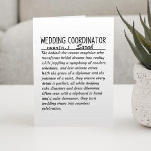 Może przedstawiać: Biała kartka z czarnym tekstem, który definiuje słowo "Wedding Coordinator" jako rzeczownik. Imię "Sarah" jest zawarte w definicji. Kartka leży na białym tle z zieloną rośliną w tle.