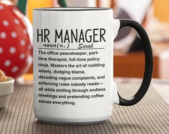 May include: White ceramic HR Manager mug with a black handle and rim. The mug features the text "HR MANAGER" above a humorous definition, including the name "Sarah". A fun gift for HR professionals.