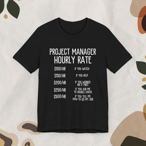 May include: Black t-shirt with white text that reads "Project Manager Hourly Rate" and a list of hourly rates with corresponding descriptions. The rates are $100/hr, $150/hr, $200/hr, $250/hr, and $500/hr.