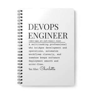 Może przedstawiać: Biały notatnik w spiralę z napisem "DEVOPS ENGINEER" pogrubioną czcionką. Poniżej wydrukowano definicję inżyniera DevOps oraz imię "Charlotte".