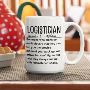 May include: White ceramic mug with a black graphic that defines the word "Logistician" as someone who plans so meticulously that they can tell you the precise moment your package will arrive, but can't figure out how they always end up with mismatched socks. The name Stephanie is included in the definition.
