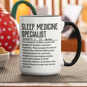 Może przedstawiać: Biały kubek do kawy z czarnym uchwytem. Kubek ma czarny tekst, który brzmi "SLEEP MEDICINE SPECIALIST noun(n.) Dr. Andrea The whisperer of ZZZs, armed with gadgets to decipher nocturnal mysteries. They navigate the land of dreams like a GPS for REM cycles, offering potions for insomniac dragons and serenading restless souls with lullabies of CPAP machines. Masters of slumber, they ensure dreams are epic and snores are silent."