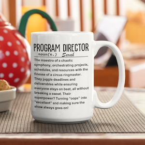 Può includere: Una tazza da caffè in ceramica bianca con un design nero che dice "PROGRAM DIRECTOR noun(n.) Sarah The maestro of a chaotic symphony, orchestrating projects, schedules, and resources with the finesse of a circus ringmaster. They juggle deadlines and deliverables while ensuring everyone stays on beat, all without breaking a sweat. Their superpower? Turning "oops" into "excellent" and making sure the show always goes on!"