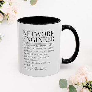 Peut inclure: Une tasse en céramique blanche avec une anse noire et le texte "But First, Coffee" en noir, dans une police manuscrite. La tasse est sur une surface blanche.
