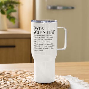 Peut inclure: Mug de voyage blanc avec une poignée et un couvercle argenté. Le mug porte l'inscription "DATA SCIENTIST" avec une définition en dessous. Le mug est conçu pour garder les boissons chaudes ou froides.