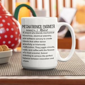 Può includere: Tazza in ceramica bianca con la scritta "MECHATRONICS ENGINEER" e una definizione. La definizione descrive un ingegnere meccatronico come un mago che combina know-how meccanico e stregoneria software. La tazza ha un manico grande.