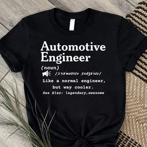 Peut inclure: Un t-shirt noir à manches courtes avec le texte blanc suivant : Automotive Engineer (noun) /ˌɔːtəˈmoʊtɪv ˌɛndʒəˈnɪr/ Like a normal engineer, but way cooler. See Also: legendary, awesome. Le t-shirt comporte une petite icône de mégaphone.