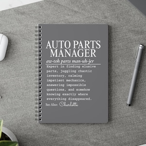 Puede incluir: Un cuaderno de espiral gris oscuro con texto en blanco que dice: AUTO PARTS MANAGER, aw-toh parts man-uh-jer, Expert in finding elusive parts, juggling chaotic inventory, calming impatient mechanics, answering impossible questions, and somehow knowing exactly where everything disappeared. See Also: Charlotte.