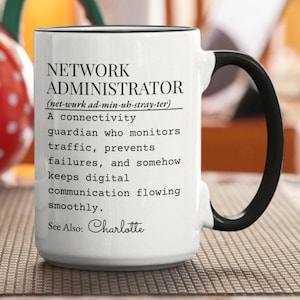 May include: A white ceramic mug with a black handle and rim, featuring black printed text that defines a Network Administrator as a connectivity guardian who monitors traffic, prevents failures, and keeps digital communication flowing, with the name Charlotte.
