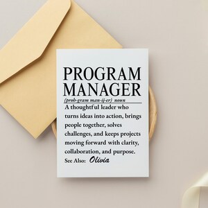 May include: A white rectangular card featuring the black printed text Program Manager, a phonetic pronunciation, and a definition describing a leader who turns ideas into action, solves challenges, and keeps projects moving with purpose. See Also: Olivia.