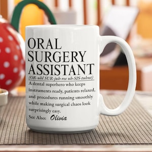 Könnte beinhalten: Ein weißer Keramikbecher mit schwarzem Aufdruck: ORAL SURGERY ASSISTANT (OR-uhl SUR-juh-ree uh-SIS-tuhnt) A dental superhero who keeps instruments ready, patients relaxed, and procedures running smoothly while making surgical chaos look surprisingly easy. See Also: Olivia