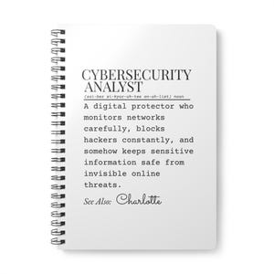 Puede incluir: Un cuaderno blanco con espiral con el texto "CYBERSECURITY ANALYST" y una definición. La definición describe a un protector digital que monitorea redes, bloquea a los hackers y mantiene la información segura. También está presente el texto "See Also: Charlotte".