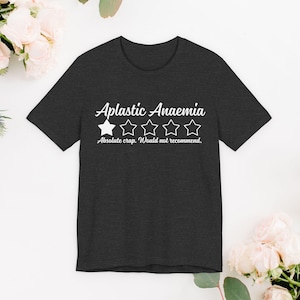 Può includere: T-shirt grigio scuro con la scritta "Aplastic Anaemia" in corsivo sopra una valutazione a una stella. Sotto la valutazione c'è il testo "Absolute crap. Would not recommend."