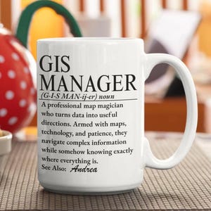 May include: A white ceramic mug featuring black printed text that defines a GIS Manager as a professional map magician who turns data into useful directions, armed with maps, technology, and patience, while knowing where everything is. See Also: Andrea.