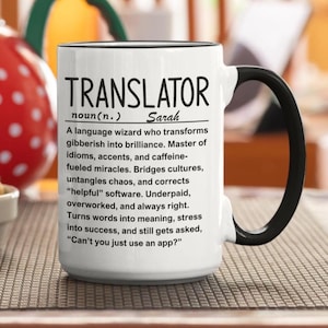 Könnte beinhalten: Ein weißer Keramikbecher mit schwarzem Henkel und Rand, bedruckt mit dem schwarzen Text: TRANSLATOR noun(n.) Sarah. A language wizard who transforms gibberish into brilliance. Master of idioms, accents, and caffeine-fueled miracles.